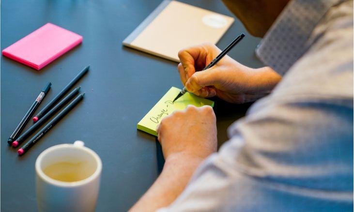 Seminar-Teilnehmerin schriebt eine Notiz auf einen Post-it